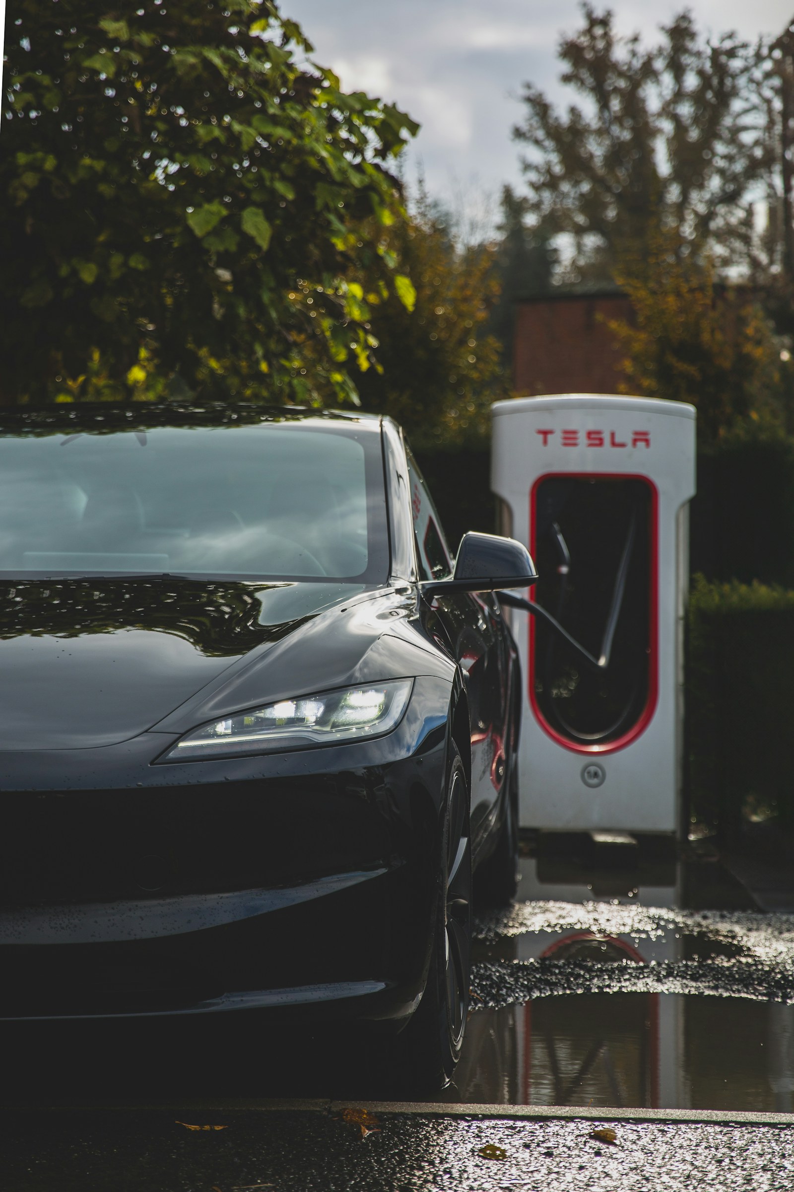 A Tesla Model 3 beside a Supercharger. Illustrative image