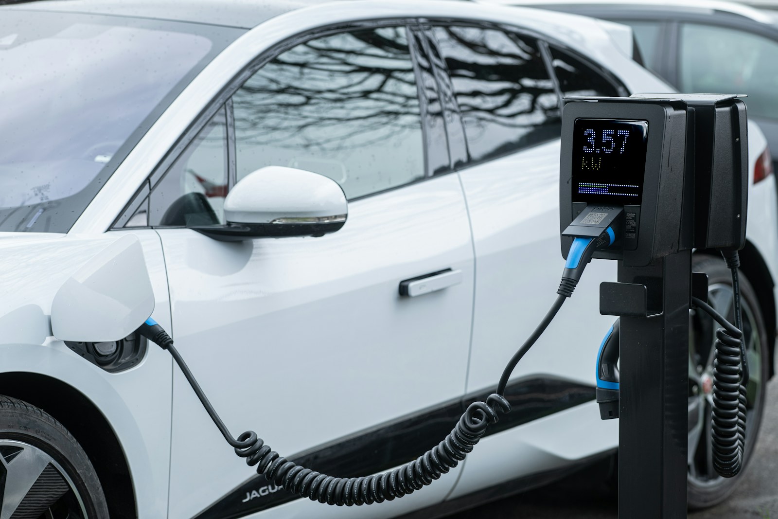A white electric car charging at a public station. Illustrative image